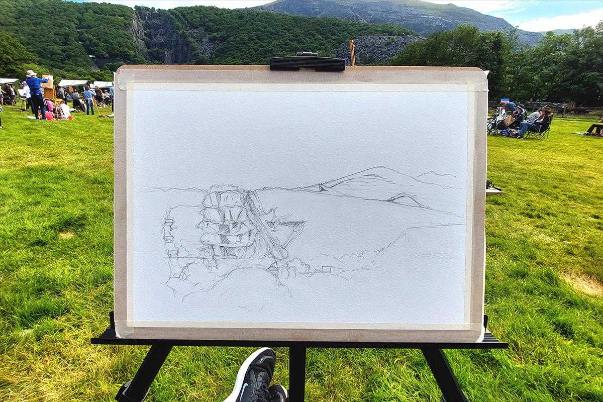 Pencil sketch outline of the landscape showing the quarry in the background. The image is mounted on a board and resting on an easle.